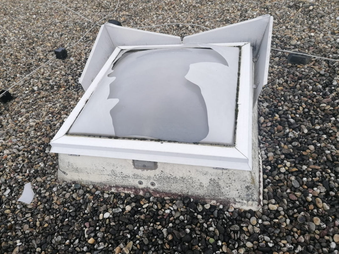 Lichtkuppel nach einem Sturm: obere Schale aufgerissen, Bruchstück auf dem Kiesdach